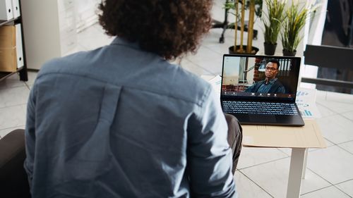 Rear view of woman using laptop at home