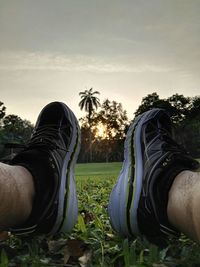 Low section of people relaxing on grass against sky