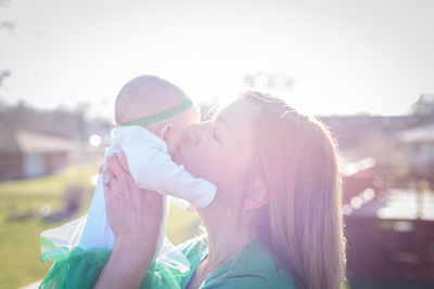 Side view of mother and daughter against clear sky