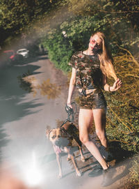 Young woman standing by dog on footpath