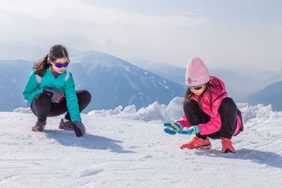 Happy young girls make snow ball on nordkette ski area of innsbruck, austria