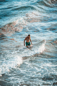 Shirtless man wading in sea