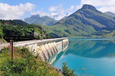 Scenic view of dam and mountains against sky