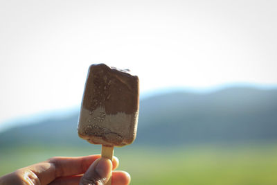 Hand holding ice cream cone against white background