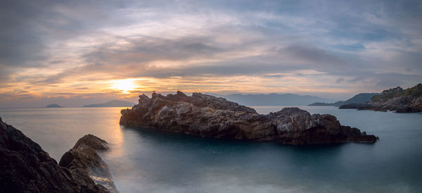 Rock formation in sea against sky during sunset