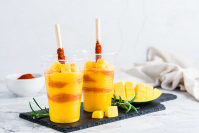 Mangonada drink made from mango and tajin chili powder in plastic glasses on the table. 