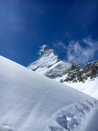 Scenic view of snowcapped mountains against blue sky