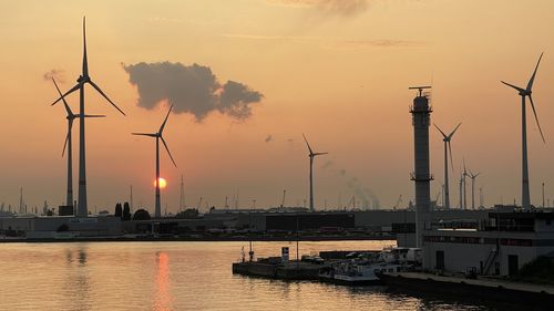 Sailboats in harbor against sky during sunset