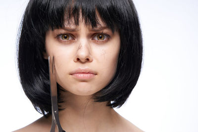 Close-up portrait of beautiful young woman against white background