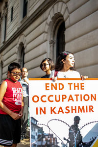 Portrait of a young couple standing against sign