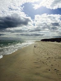 Scenic view of beach against cloudy sky