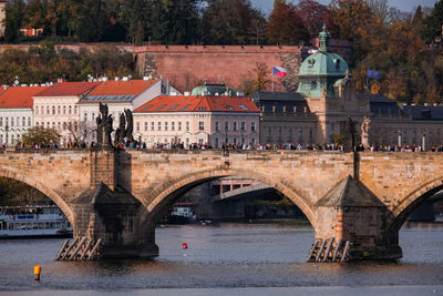 Arch bridge over river by buildings in city