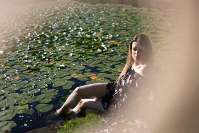 Portrait of young woman sitting by lake