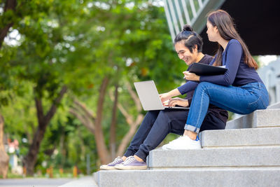 Side view of woman using mobile phone while sitting on staircase