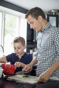 Father and son preparing food in kitchen