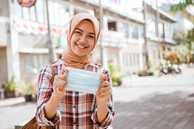 Portrait of smiling young woman standing on street