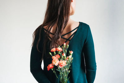 Midsection of woman holding flower bouquet against white background