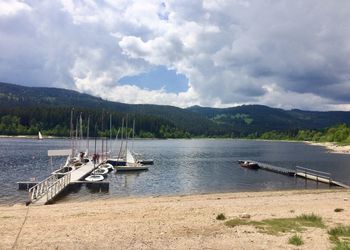 Sailboats moored on lake against sky