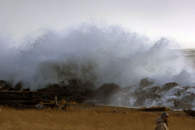 Scenic view of waves on shore against sky