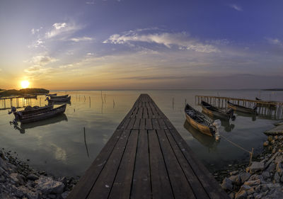 Pier over sea against sky during sunset