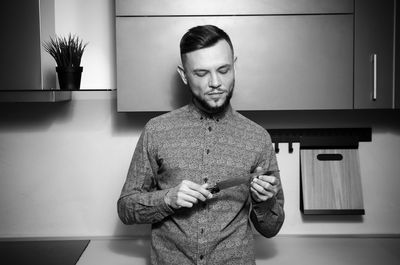 Man holding knife while standing in kitchen