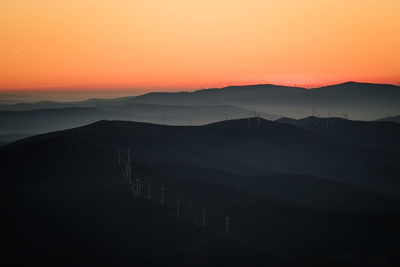 Scenic view of silhouette mountains against orange sky