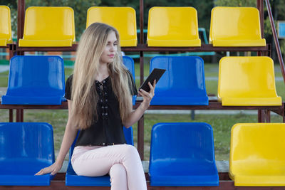 Young woman using phone while sitting on chair