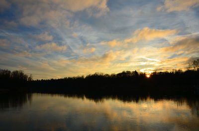 Scenic view of lake against cloudy sky during sunset