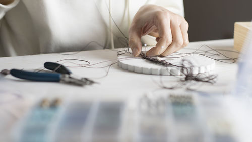 Close-up of woman working with thread on table