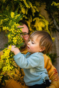 Side view of young woman standing amidst yellow flowers