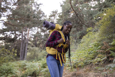 Happy woman with backpack walking in forest