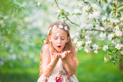 Close-up of girl with arms outstretched standing against plants