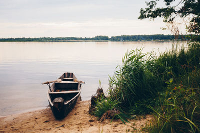 Boat moored on lake against sky