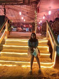 Full length portrait of woman sitting on staircase
