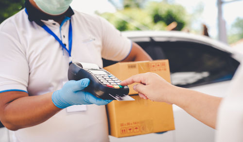 Cropped hand of customer making payment for package to delivery person