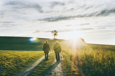 People walking on field at sunset