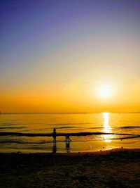 Silhouette people on beach against sky during sunset