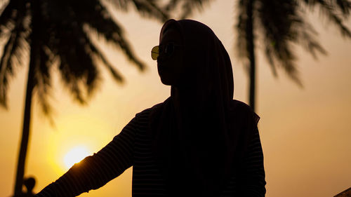 Silhouette woman standing against sky during sunset