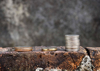 Close-up of coins stacked on brick against wall