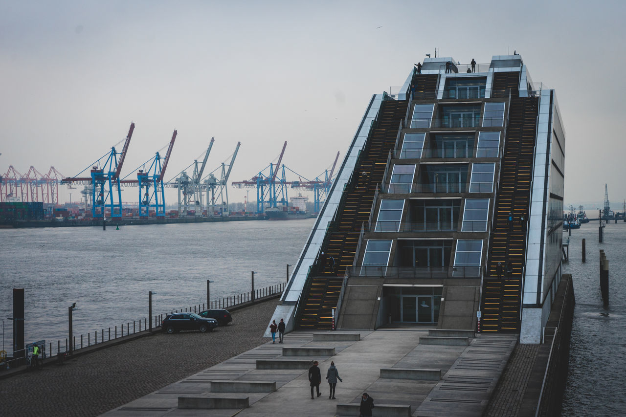 CRANES AT HARBOR AGAINST SKY