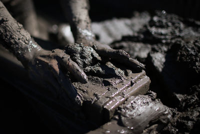 Midsection of man holding stone on mud