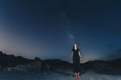 Front view of woman standing on mountain against sky at night