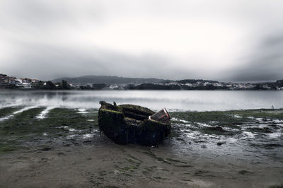 Abandoned boat at beach against sky