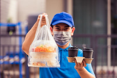 Delivery man in wearing face mask making grocery giving rice food boxes plastic bags and coffee 