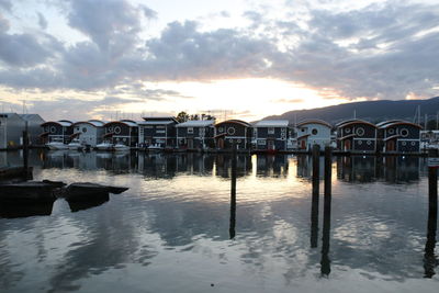 Reflection of houses in water against sky during sunset