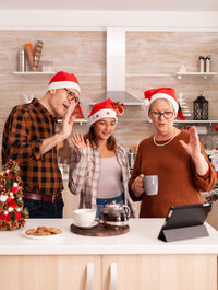 Family gesturing on video call while standing in kitchen