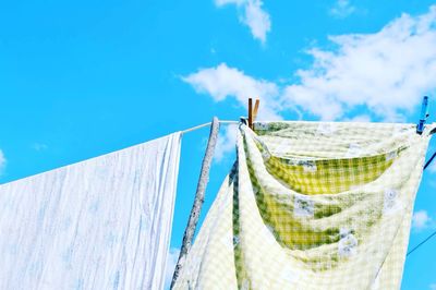 Low angle view of clothesline hanging against blue sky