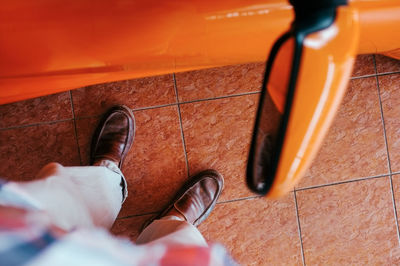 Low section of man standing on tiled floor by car