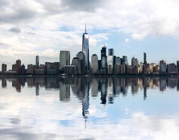 City at waterfront against cloudy sky