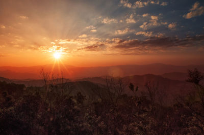 Scenic view of silhouette mountains against orange sky